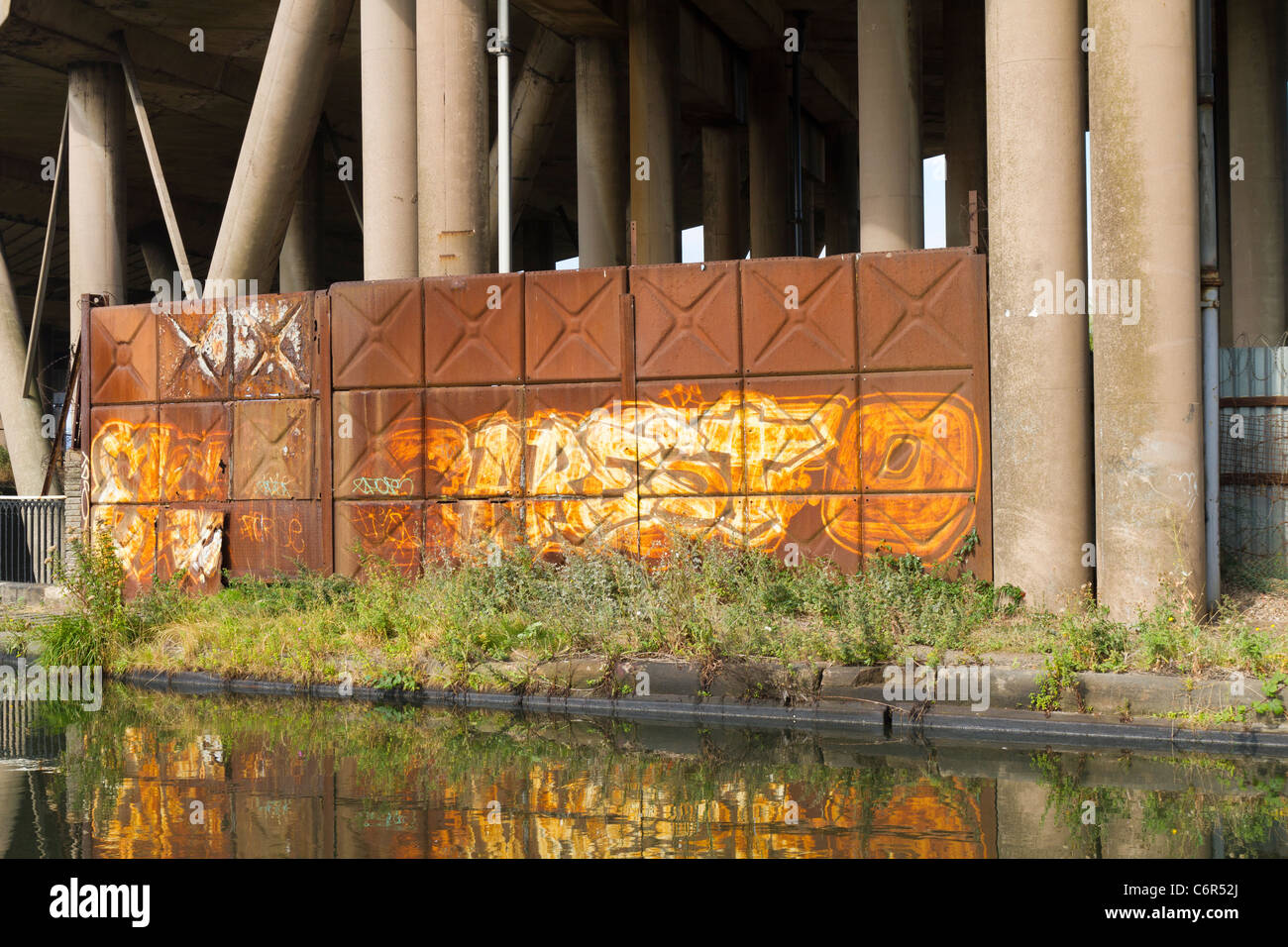Rust covered metal fencing protecting a factory below the motorway in the West Midlands Stock Photo