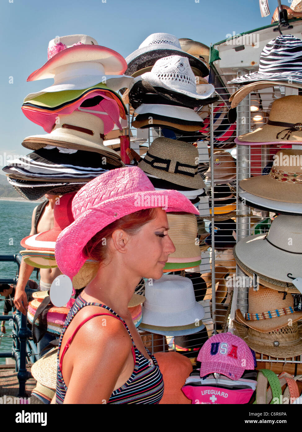 A saleswoman models her merchandise at a hat stand on Santa Monica Pier. Stock Photo
