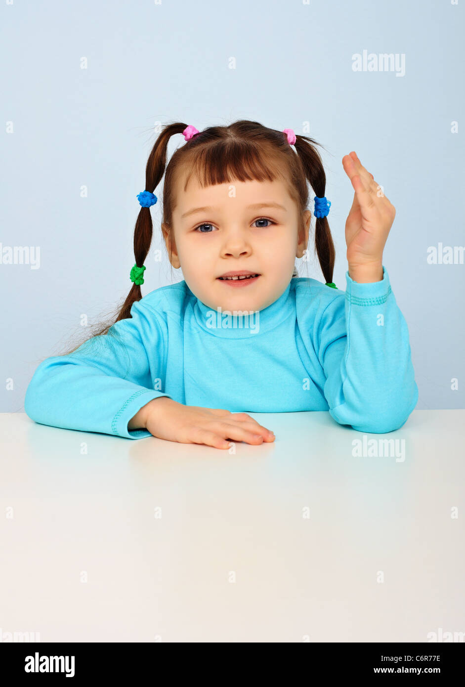 Little girl sitting at school desk on blue background Stock Photo - Alamy