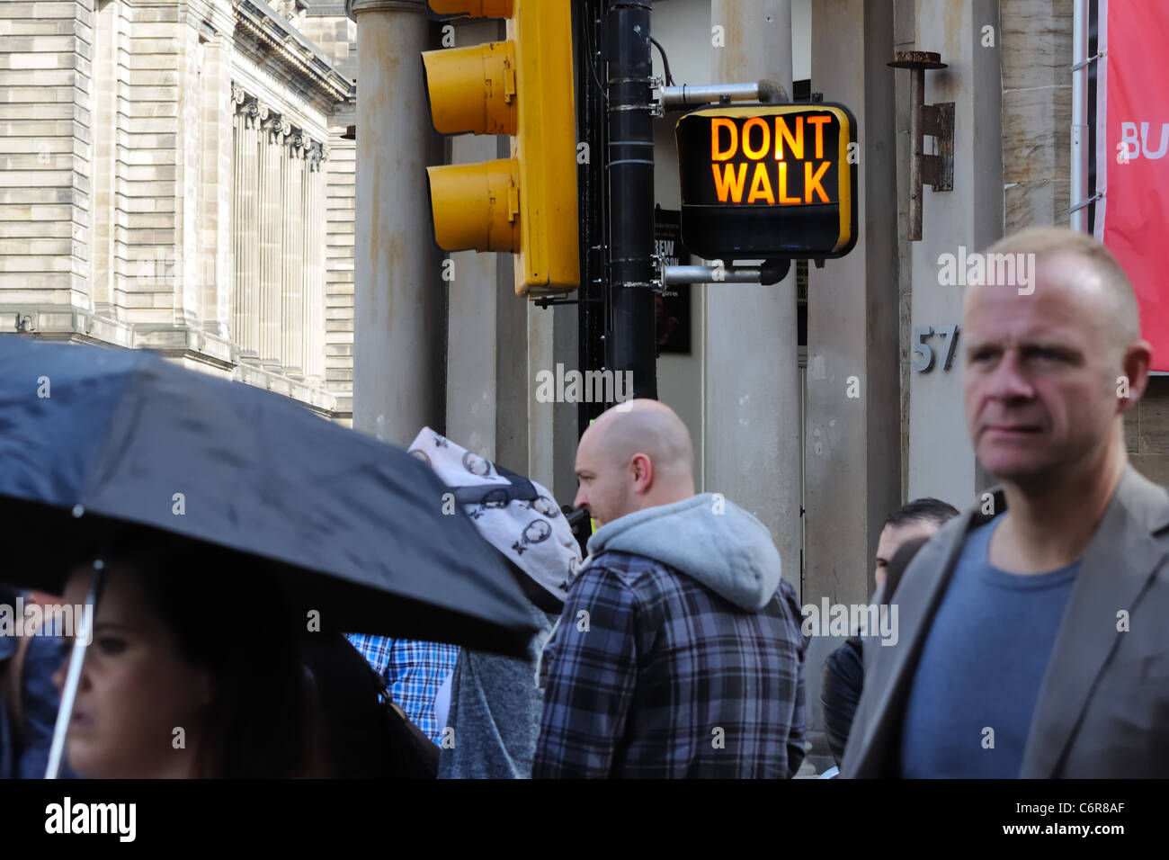 People of Glasgow walking with American traffic sign in background. Stock Photo
