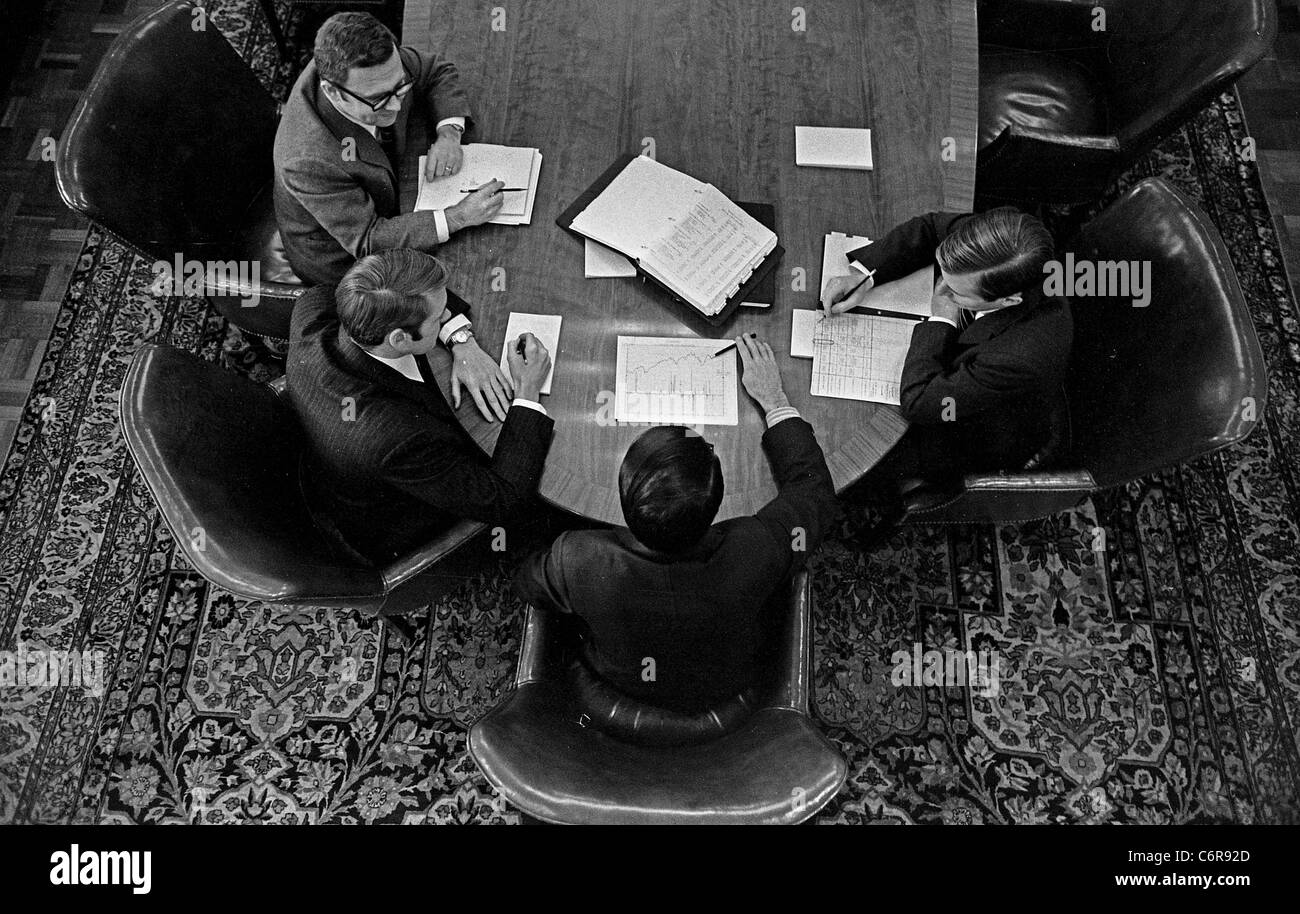 Four insurance company executives discuss graphs at a conference table in Boston. Note Persian