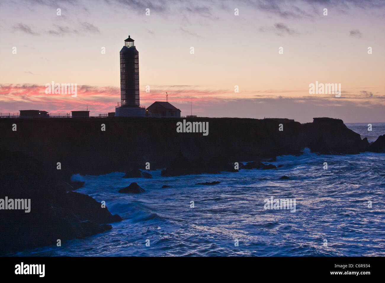 Point Arena Lighthouse in California, at sunset, with storm coming in off the pacific ocean with crashing waves. Keepers house can be rented. Stock Photo