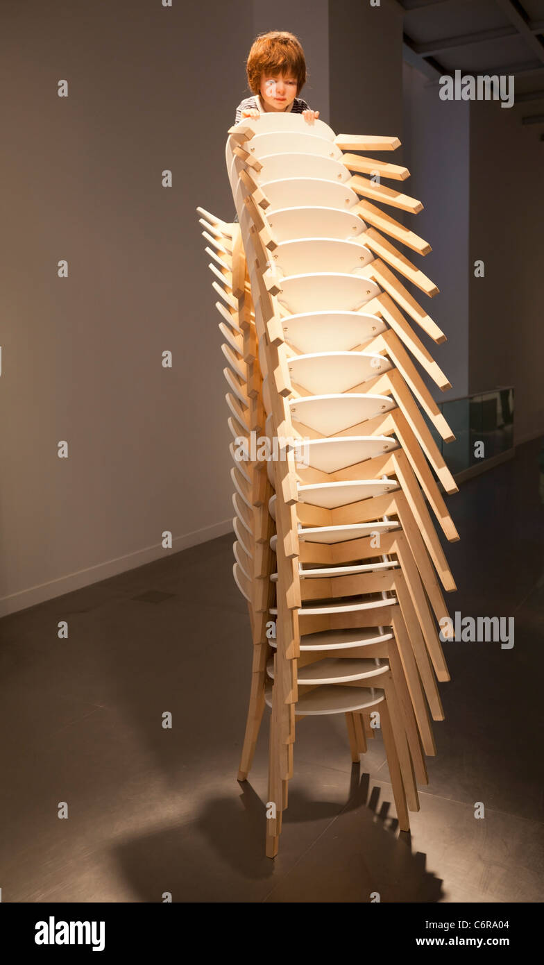 Istanbul, Turkey - June, 2011: Boy climbing chairs sculpture by Patricia Piccinini art show at Arter Gallery Stock Photo