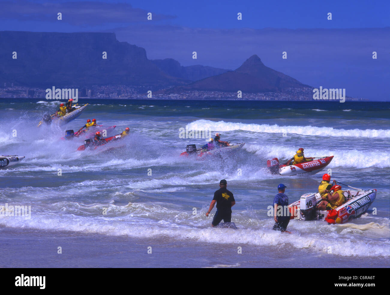 Participants in rubber dinghy race setting off into the waves with Lions head in the distance Stock Photo