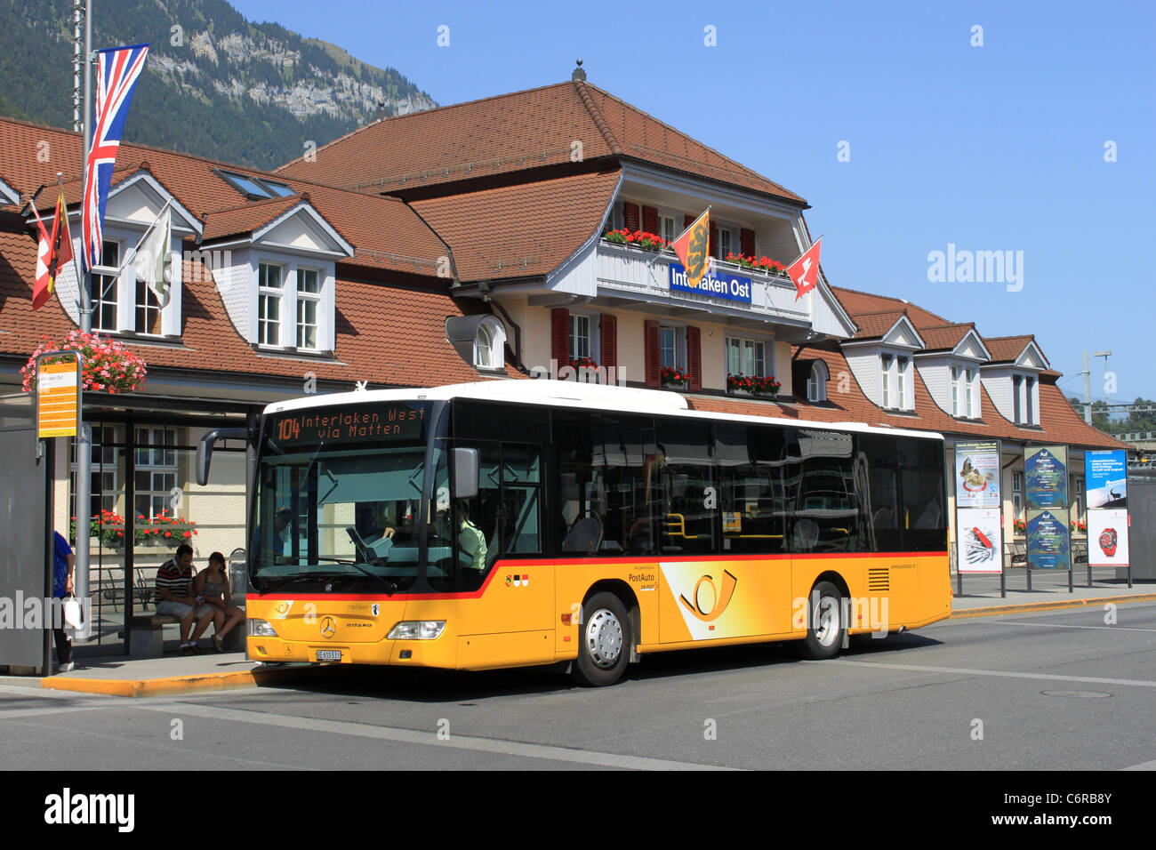 Yellow Swiss postbus waiting outside Interlaken Ost (East) railway station with a service to Interlaken West, Switzerland. Stock Photo