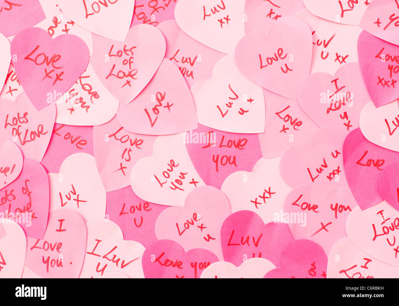 Messages of Love written on pink heart shaped Post-it note paper Stock Photo
