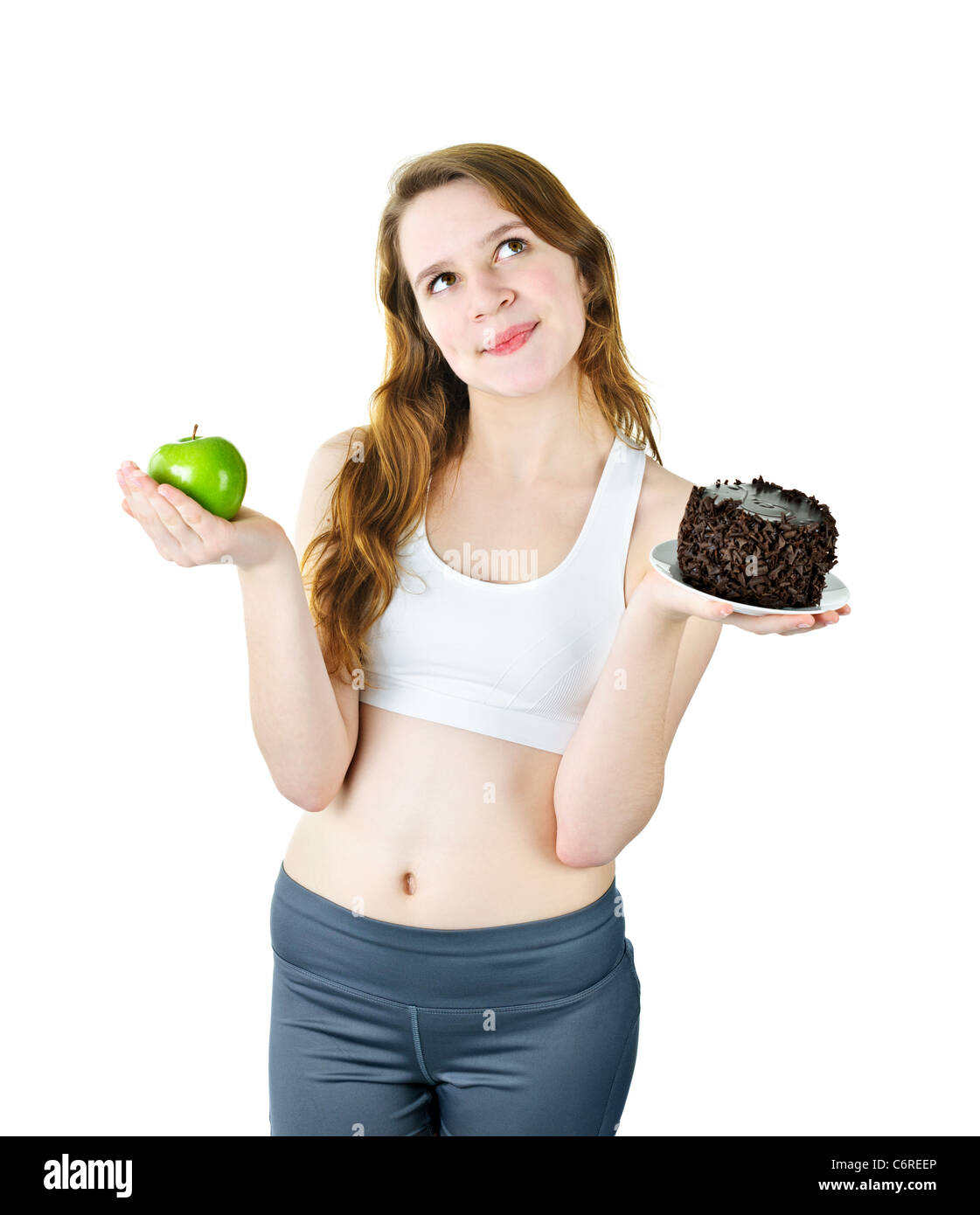 Tempted young woman holding apple and chocolate cake making a choice Stock Photo
