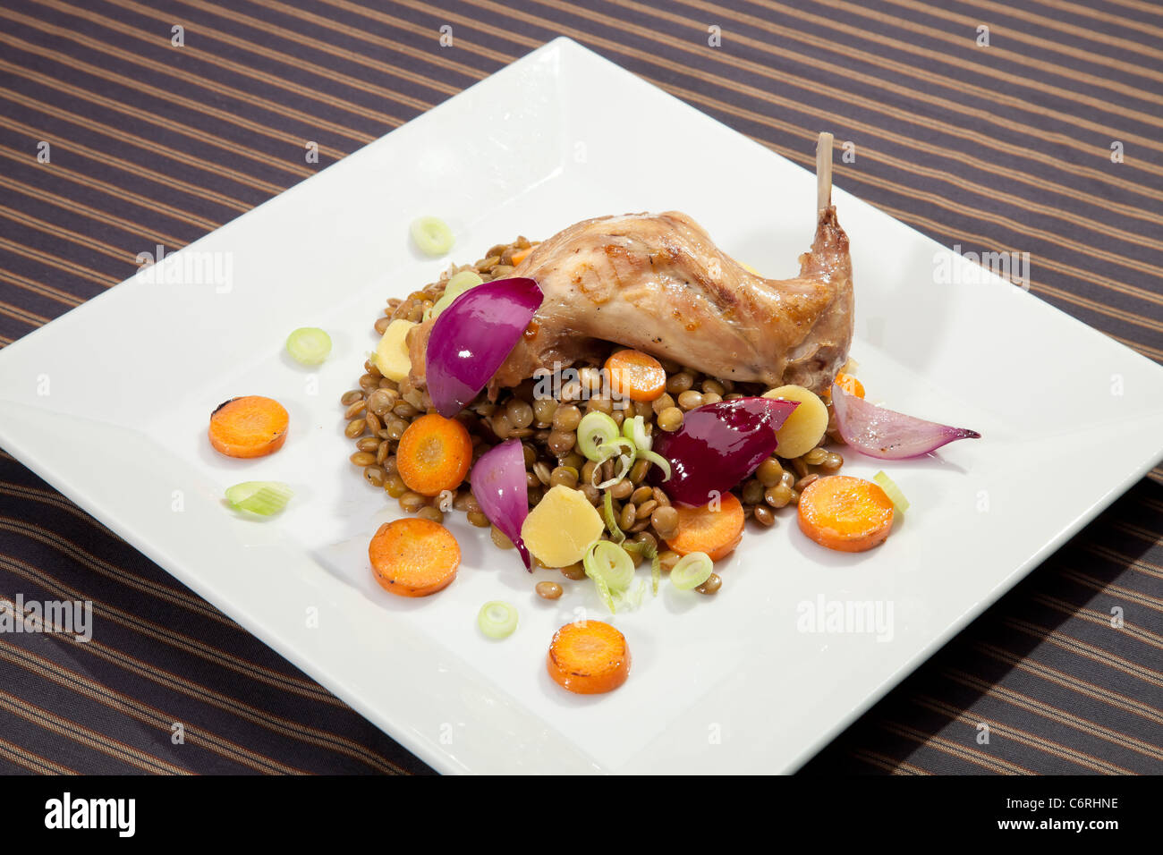Baked rabbit leg with lentil and vegetable garnish Stock Photo - Alamy