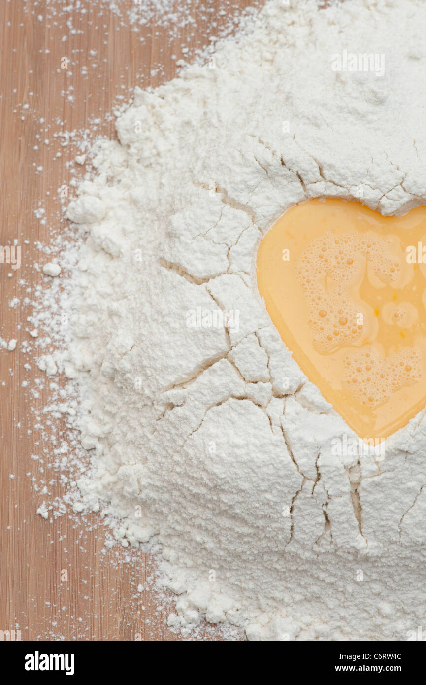 I Love to Cook concept. Heart shaped hollow filled with eggs in a pile of flour Stock Photo