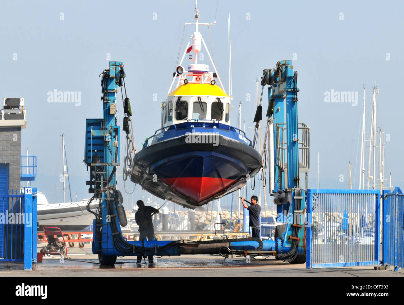 Boat cleaning, men clean the underside of a boat out of water, UK Stock Photo