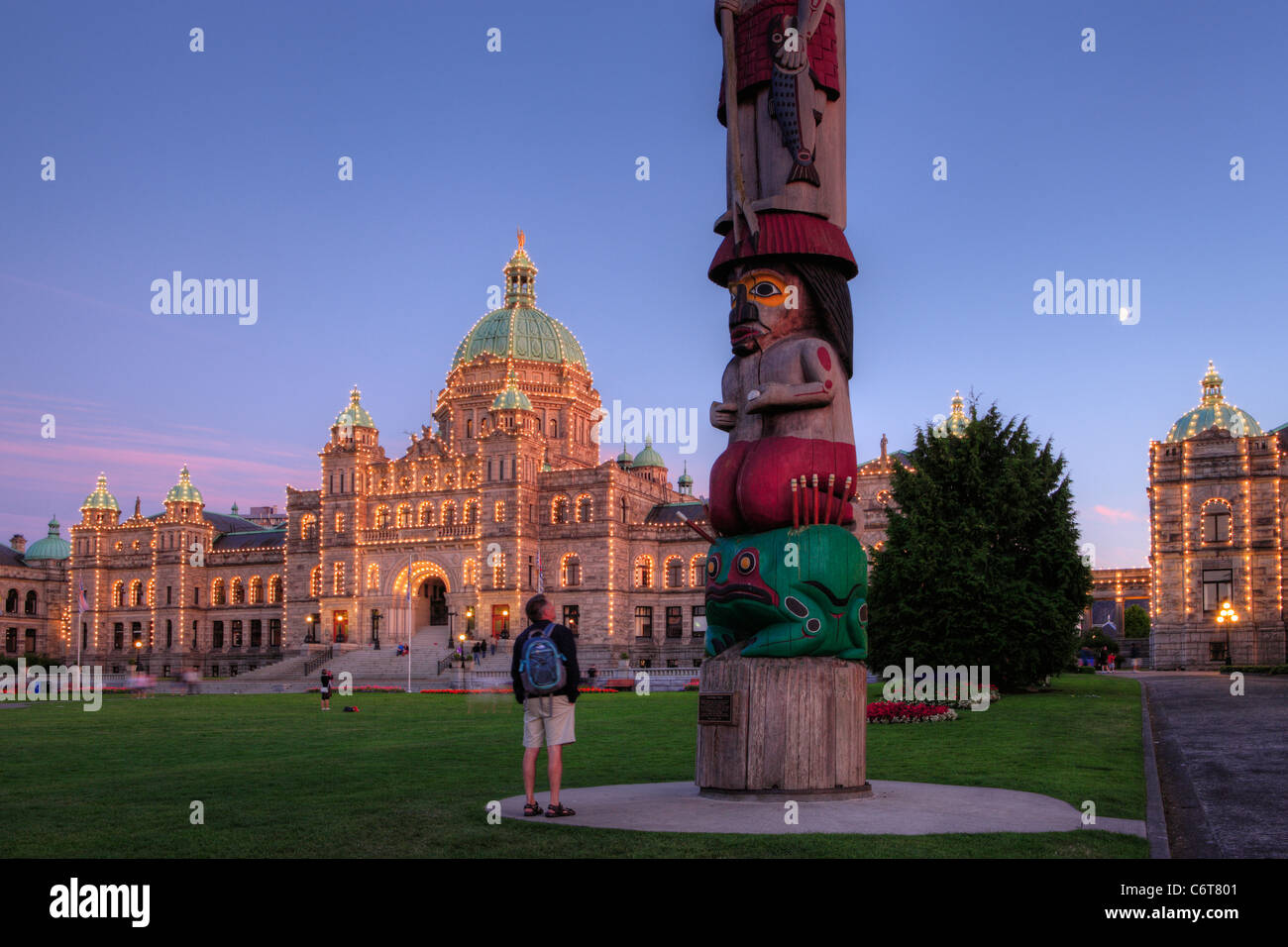 Aboriginal first nations Knowledge totem pole and Provincial legislative buildings at dusk-Victoria, British Columbia, Canada. Stock Photo