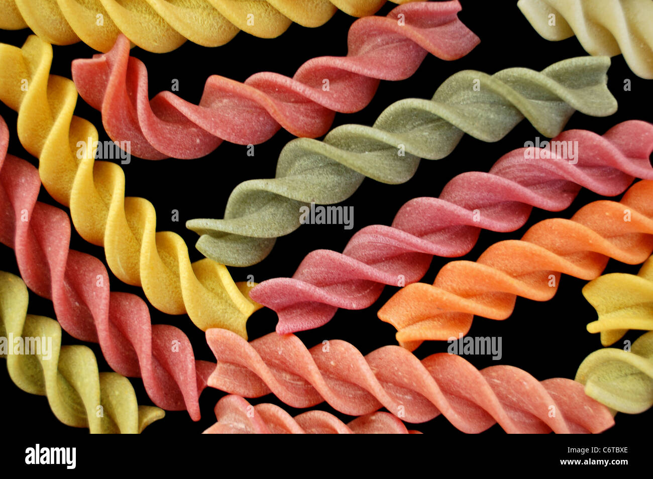 Multi colored fusilli italian pasta on black background. Creative food