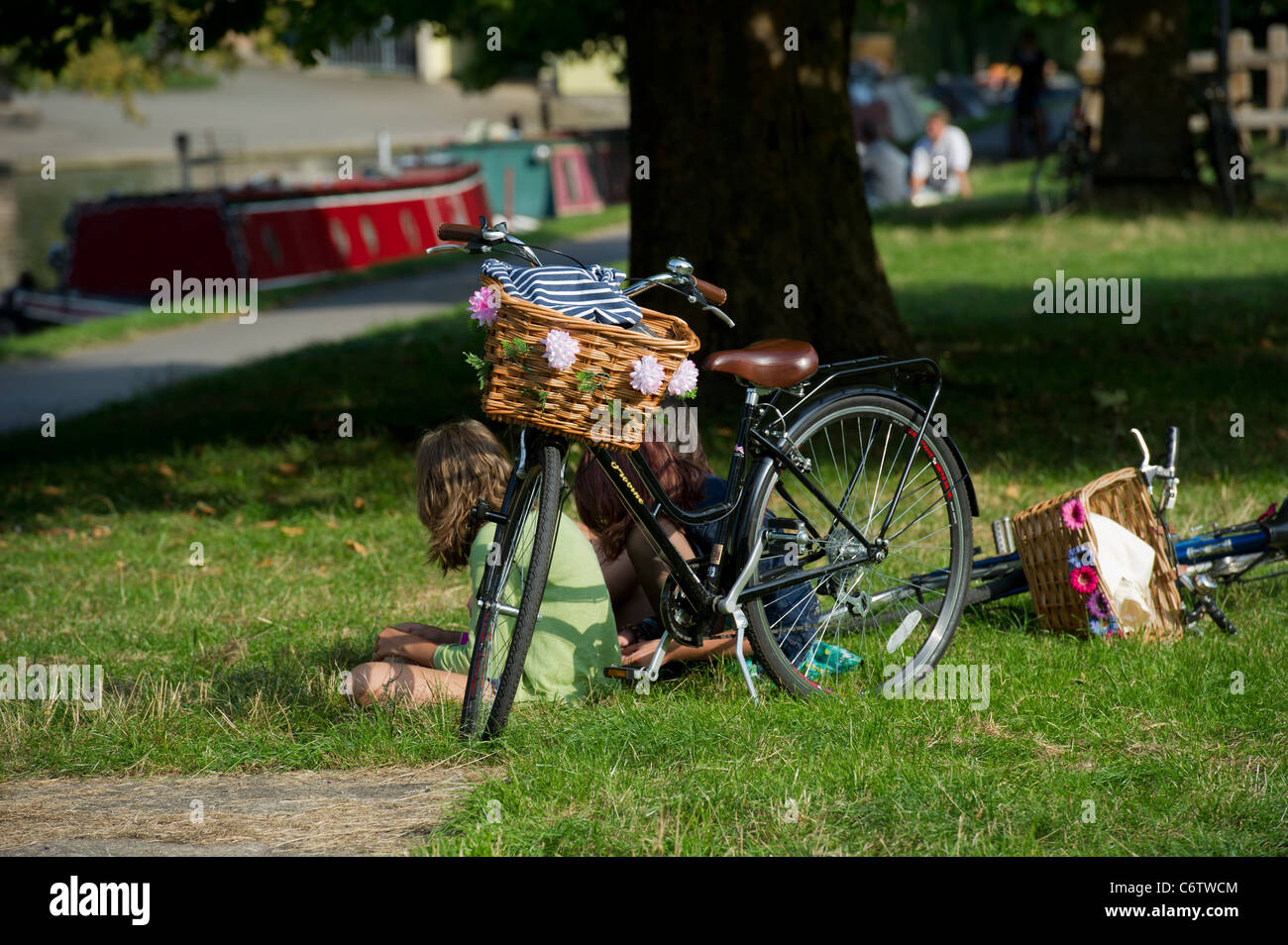 Beside the River Cam, in Cambridge, an old fashioned bicycle with basket on front decorated with flowers. Stock Photo