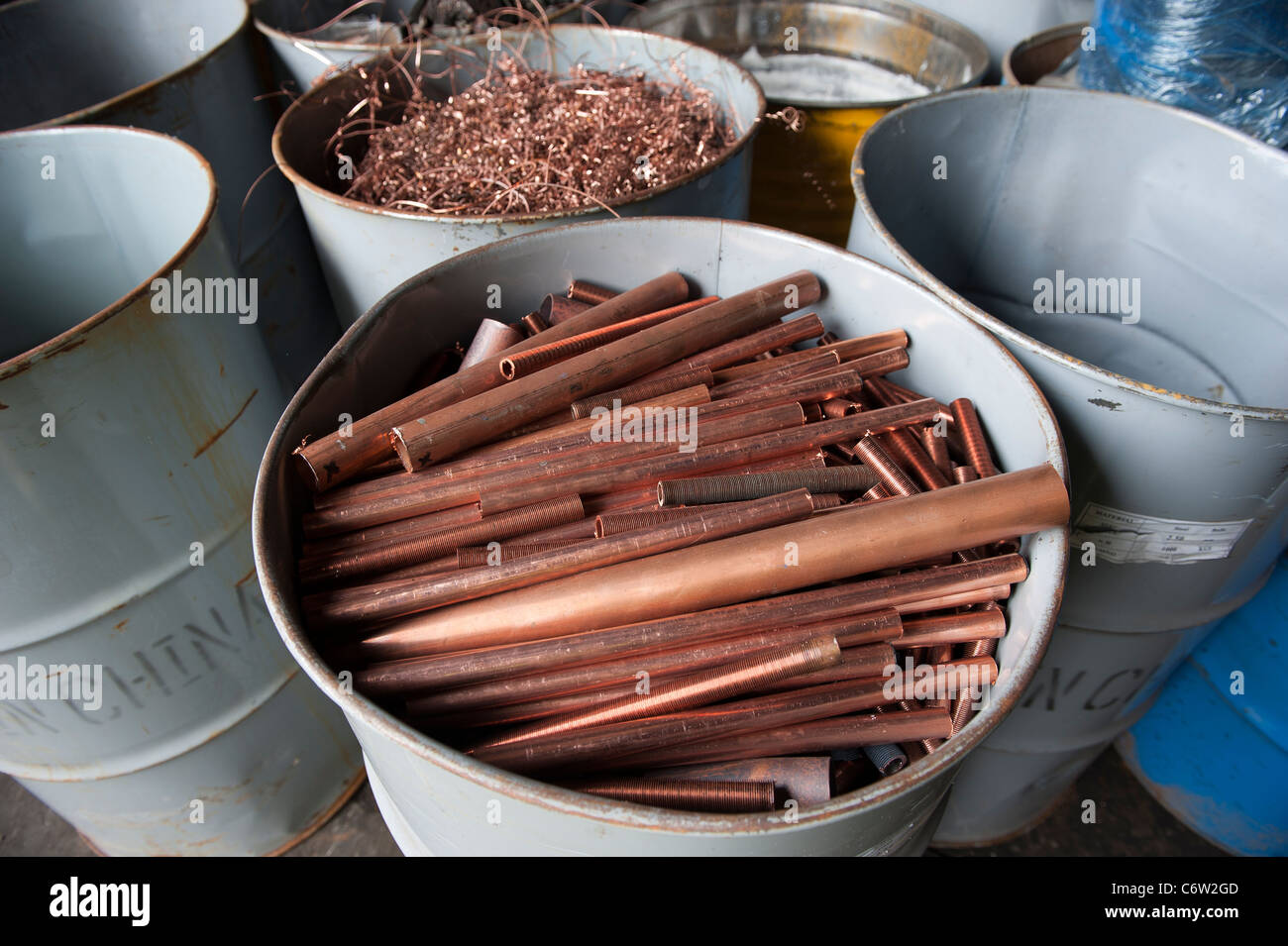 Scrap metal in a drum at a UK scrapyard. Copper piping. Stock Photo