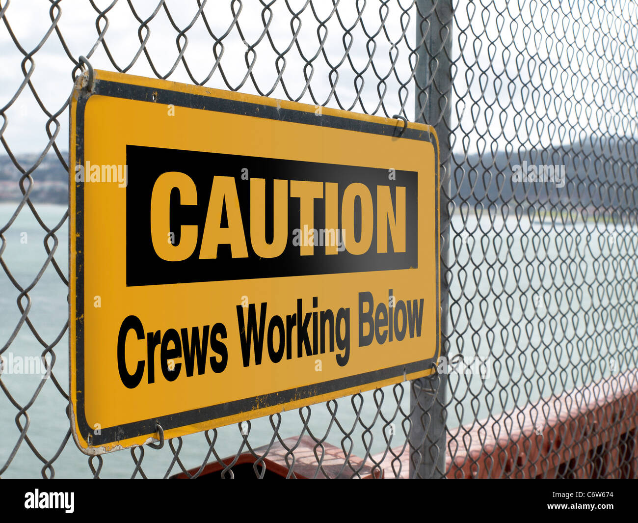 Caution Crews Working Below sign attached to a wire fence Stock Photo ...