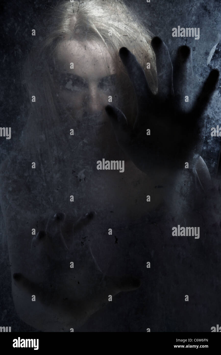 Female witch behind the dark glass Stock Photo