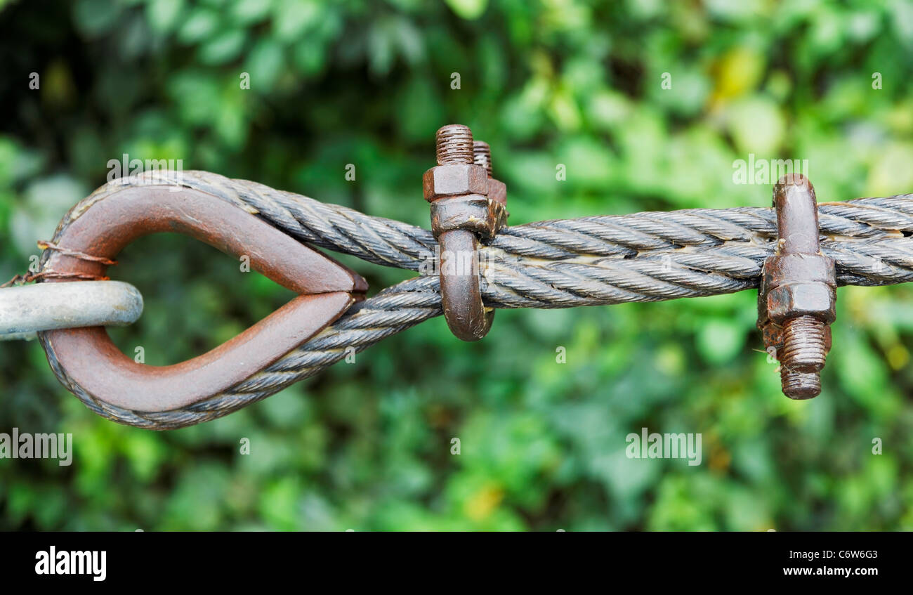 greased steel wire cable rope clamped around an eyelet with rusty U bolts linked to a galvanised clasp, structural support rope Stock Photo