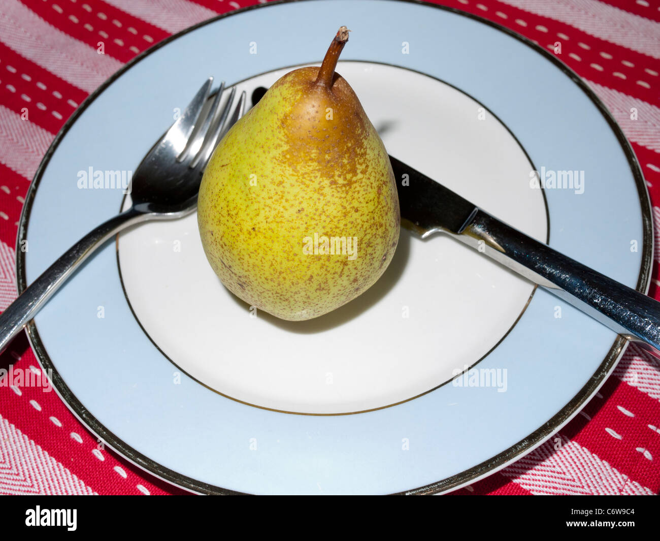 Pear on a plate with knife and fork Stock Photo