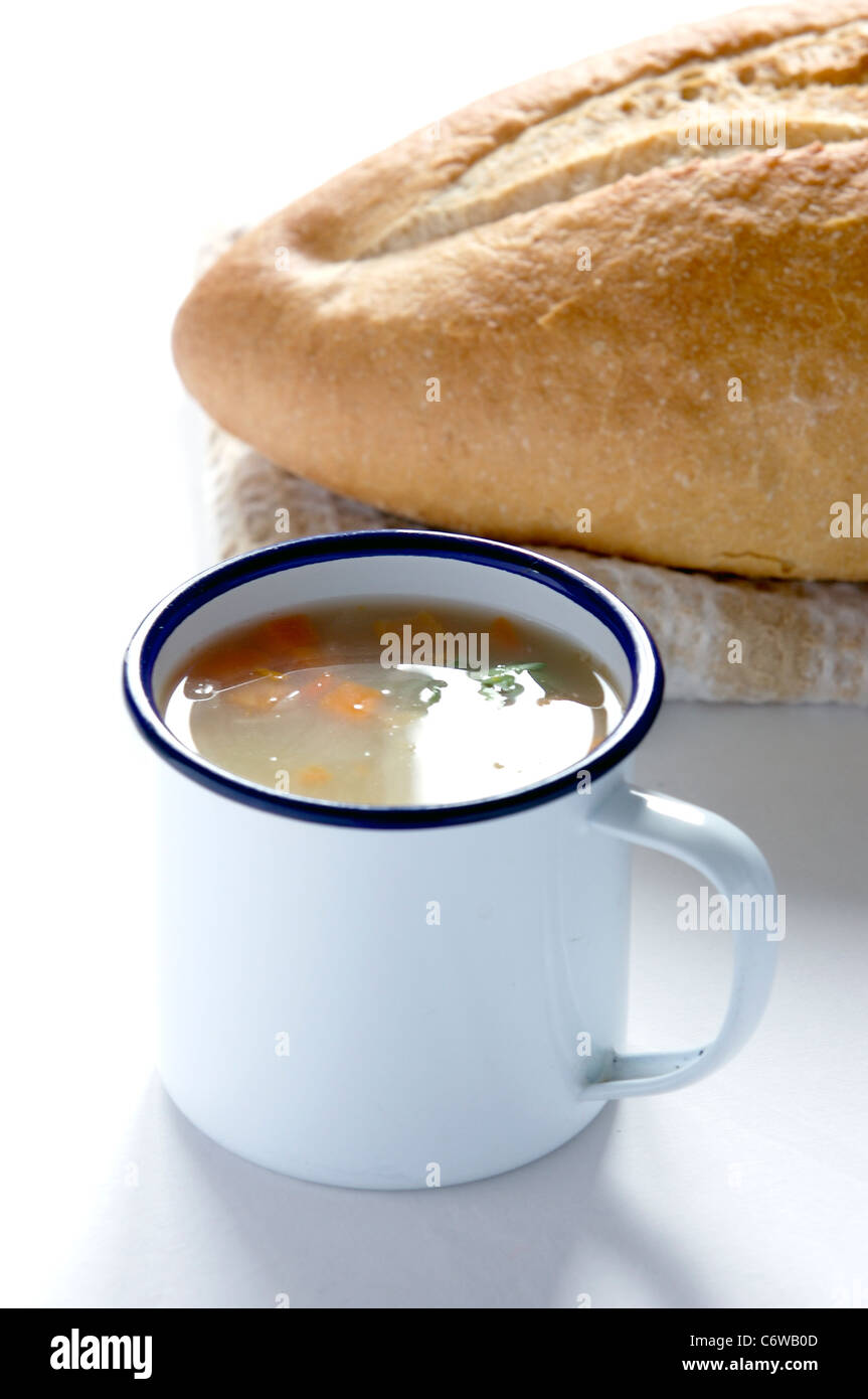Enamel mug with chicken and vegetable soup and a french paysanne loaf Stock Photo