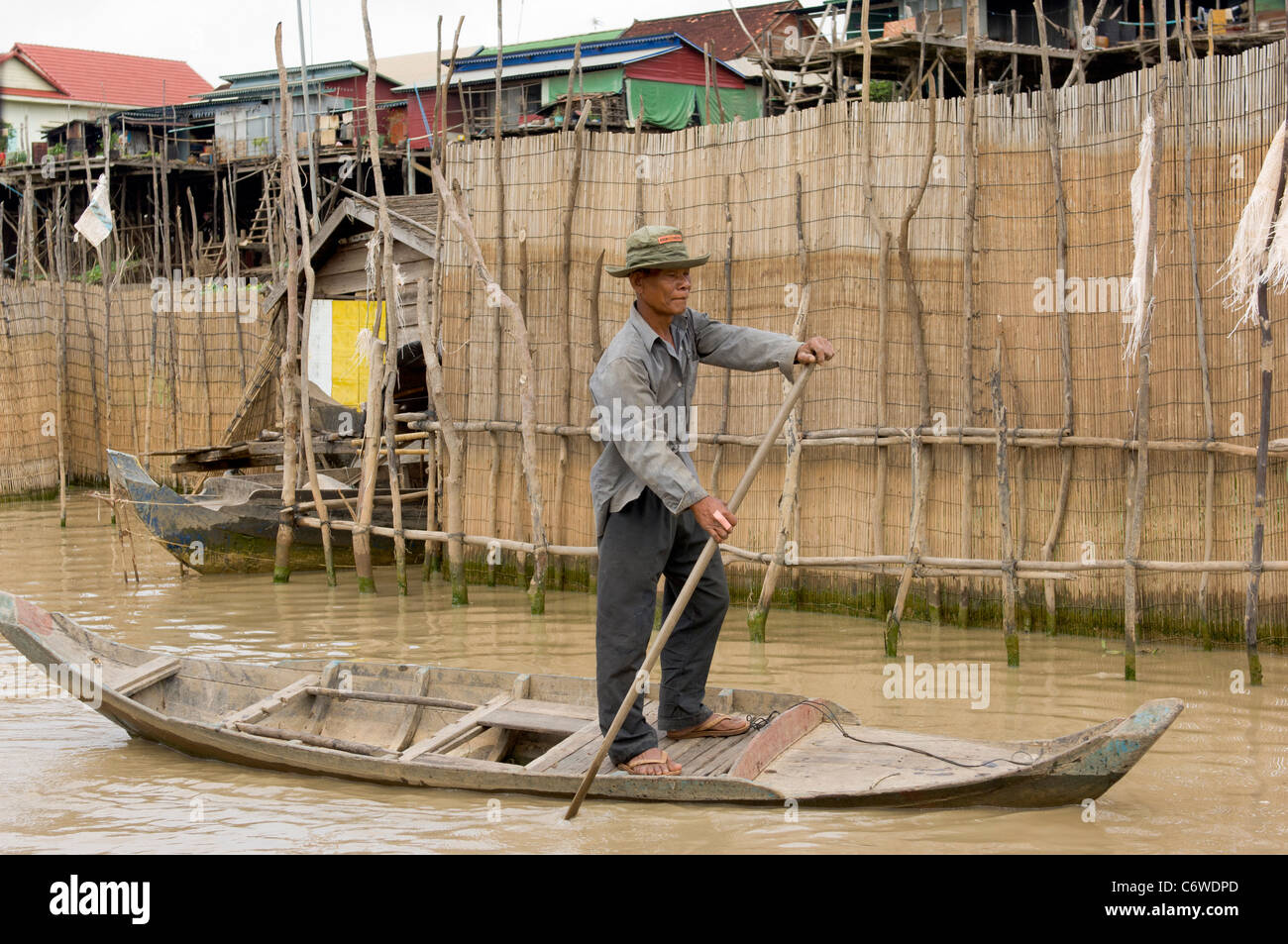 Standing man poling a boat in a tributary of Tonle Sap lake, at Kompong Klang village near Siem Reap, Cambodia Stock Photo
