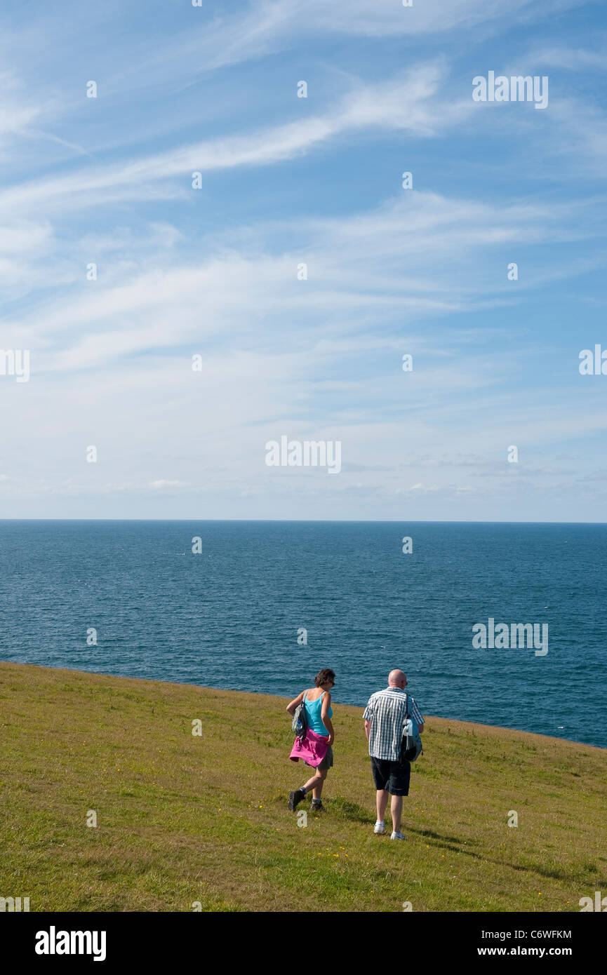 Couple enjoying a day out walking along the cliff top on a summers day in Cornwall, England. Stock Photo