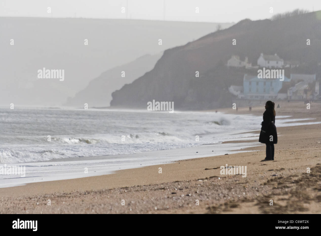 A woman stands on the beach looking out to sea Stock Photo - Alamy
