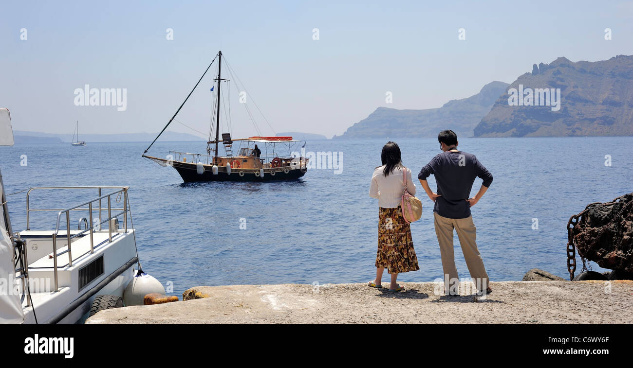Santorini Cyclades Islands, Greece, Asian couple waiting a tourist boat in Fira Stock Photo