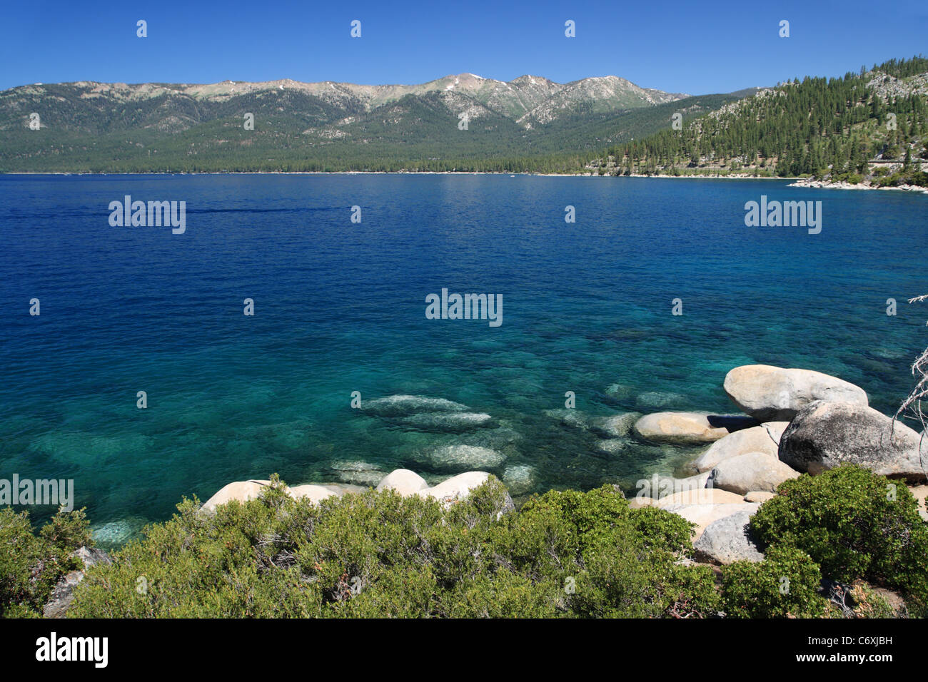 blue Lake Tahoe landscape with rocky shore and distant mountains Stock Photo