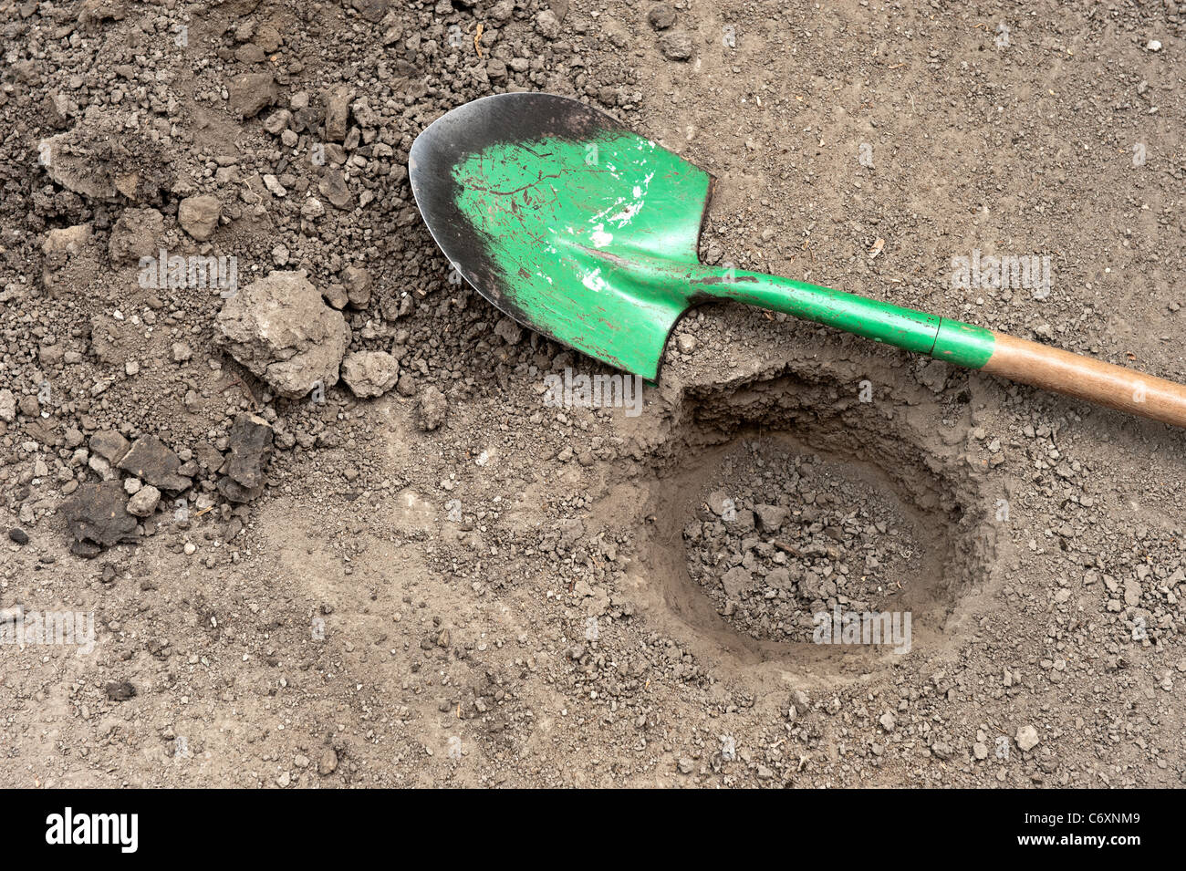 A hole in the dirt with shovel on ground. Stock Photo