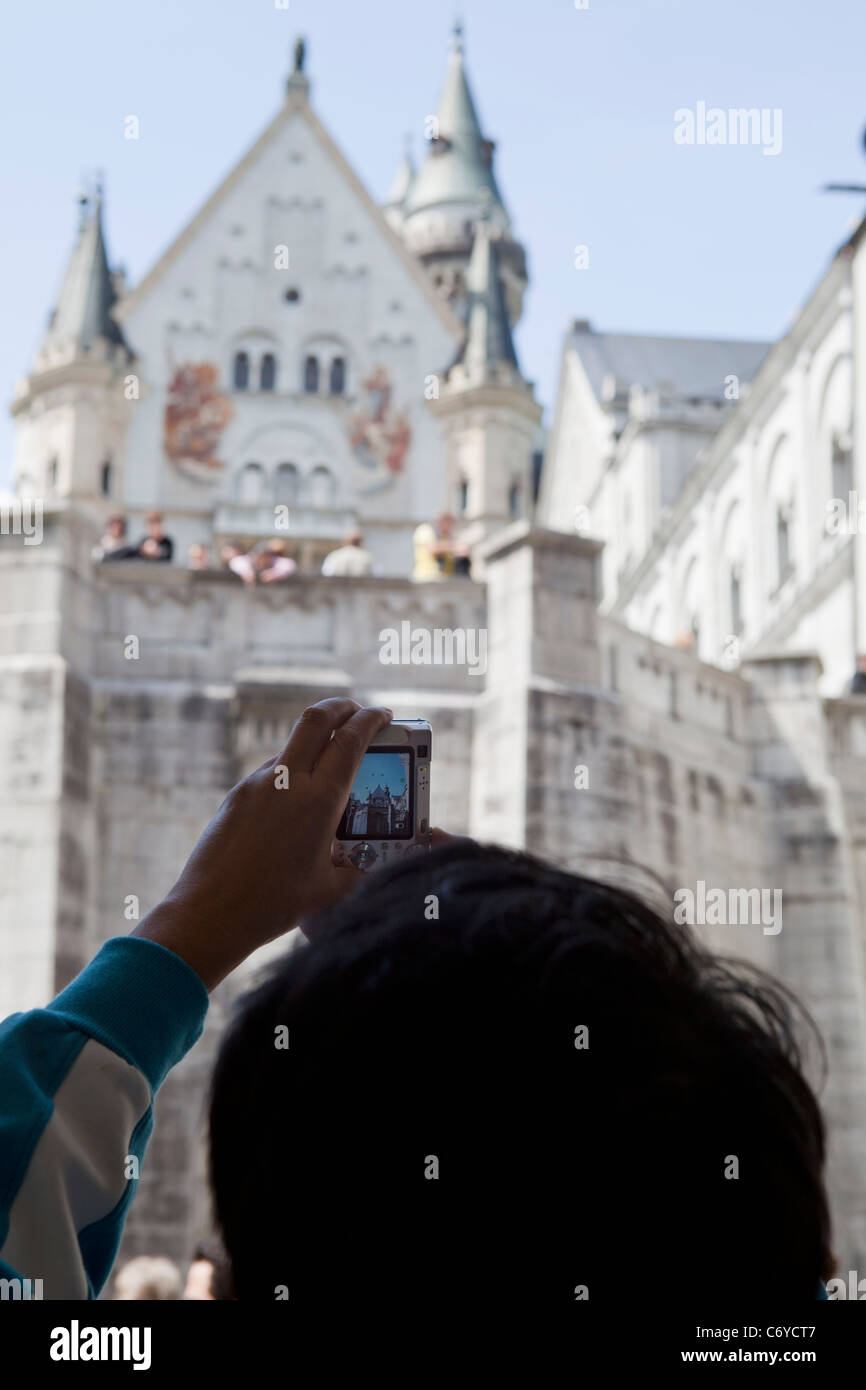 Tourist taking pictures of Neuschwanstein castle with digital camera. Bavaria Germany Stock Photo