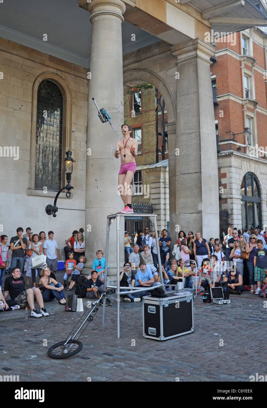 Busker male performer juggling with a chain saw in Covent Garden London UK Stock Photo