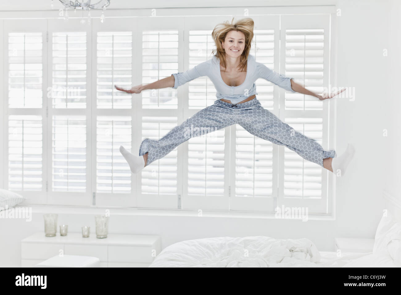Woman jumping on bed Stock Photo