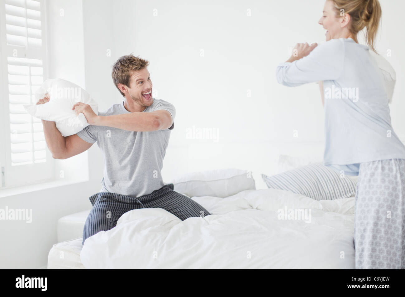 Couple having a pillow fight in bedroom Stock Photo