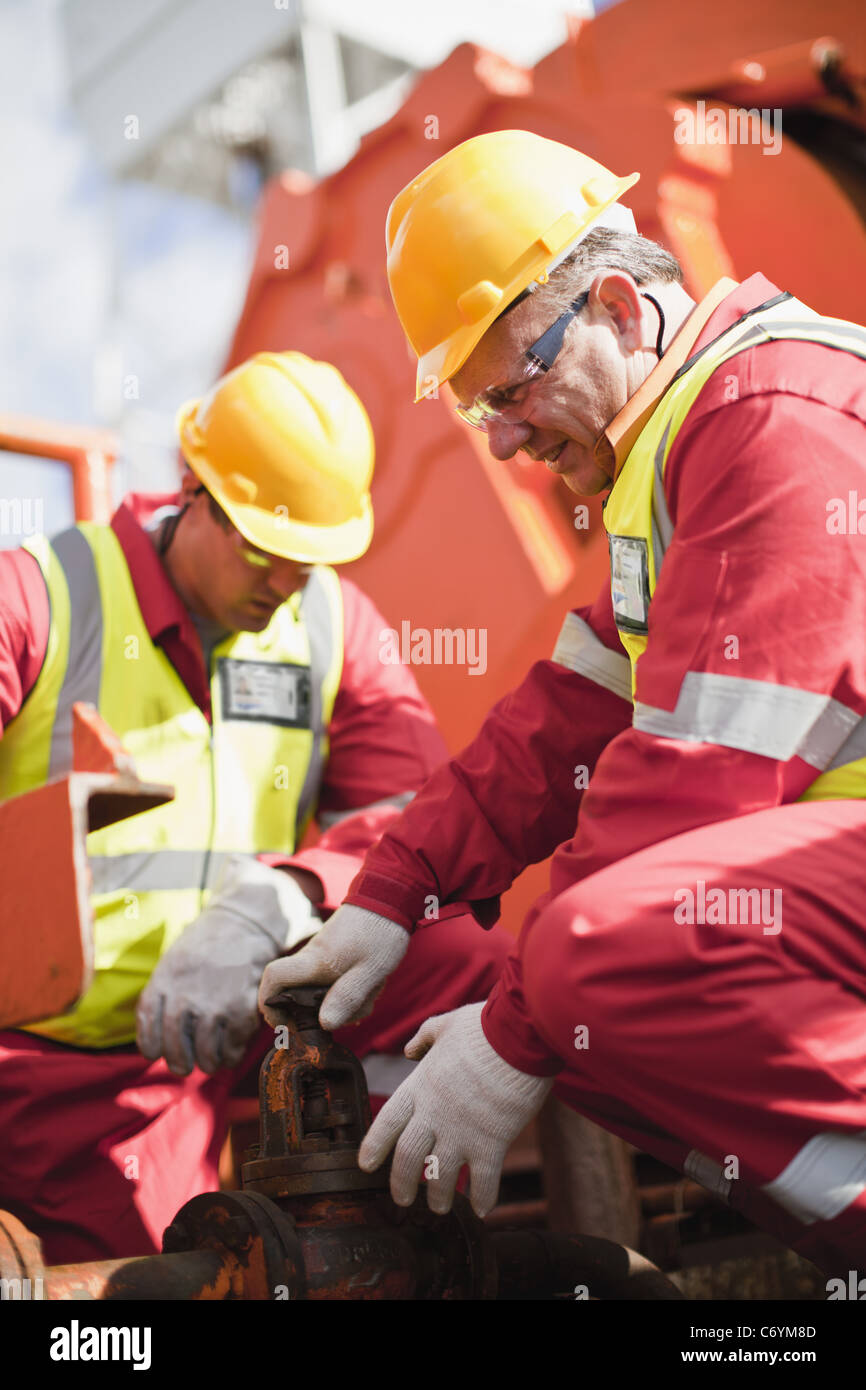 Worker turning wheel on oil rig Stock Photo