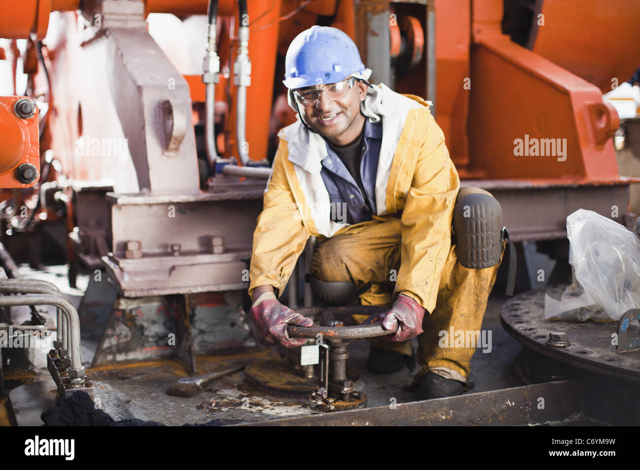 Worker turning wheel on oil rig Stock Photo