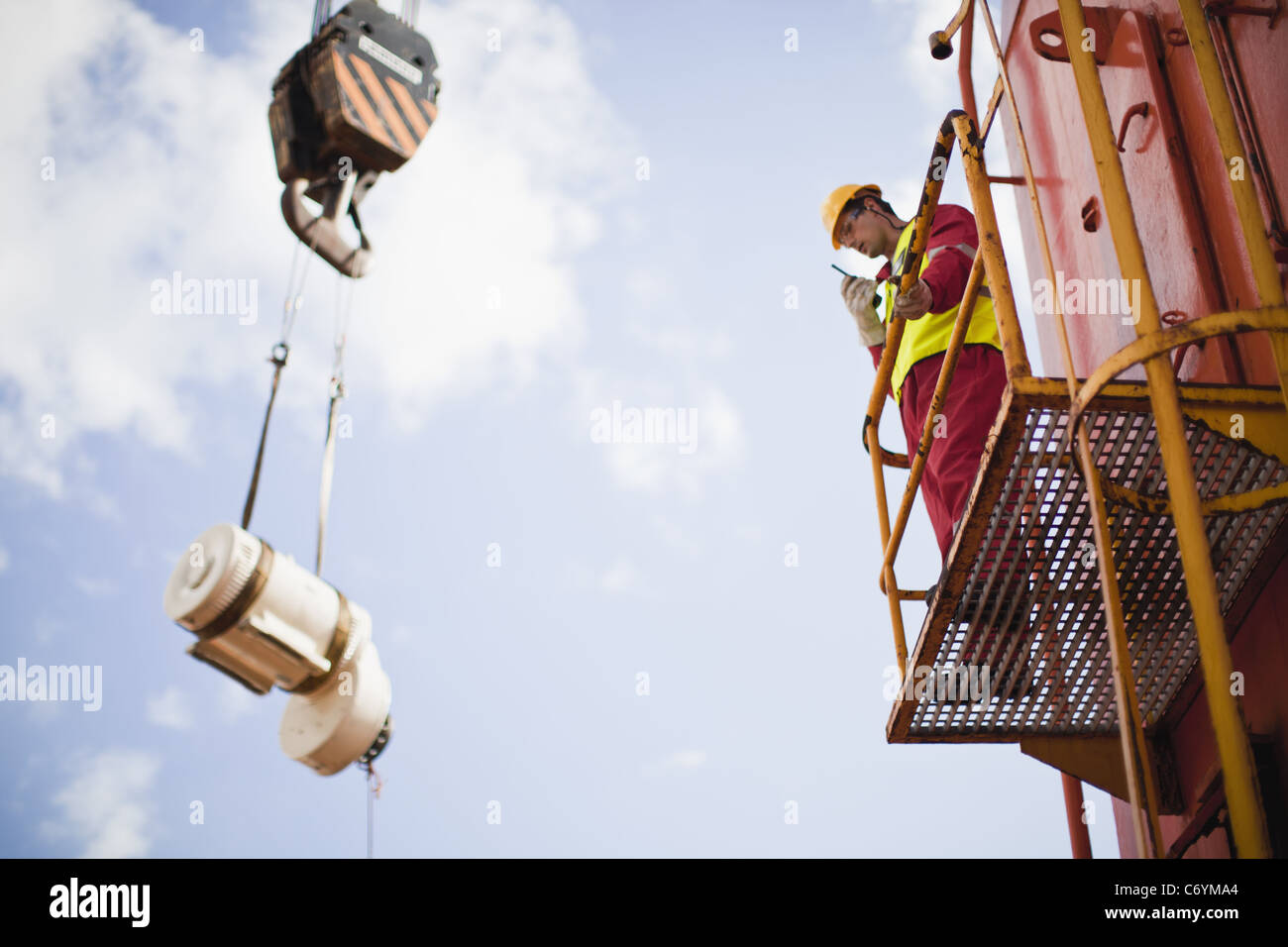 Worker directing crane on oil rig Stock Photo Alamy