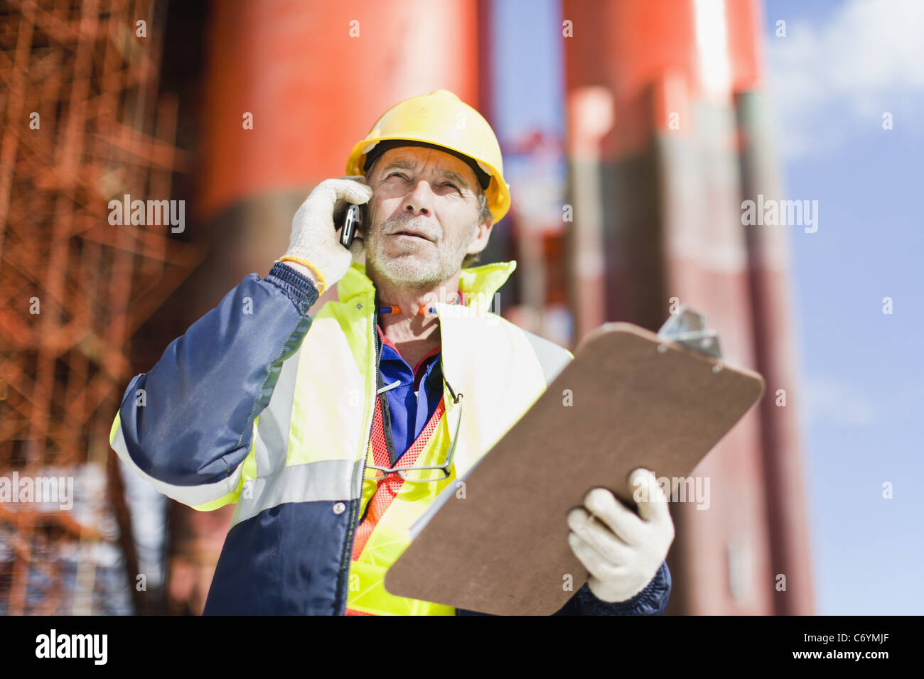 Worker talking on cell phone on oil rig Stock Photo
