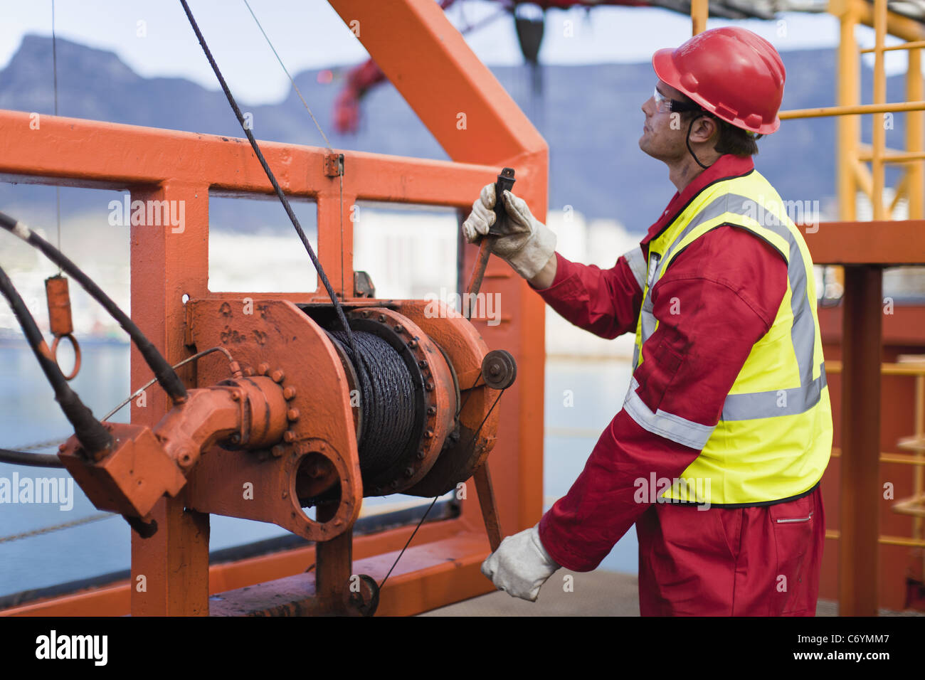 Worker spooling cord on oil rig Stock Photo