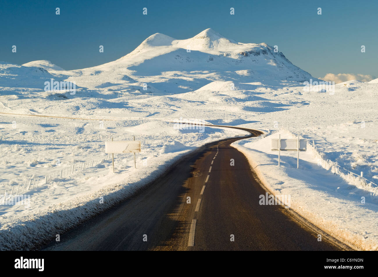 A837 road leading across frozen moorland in front of Cul Mor (849 metres), looking southwest from Ledmore Junction. Stock Photo
