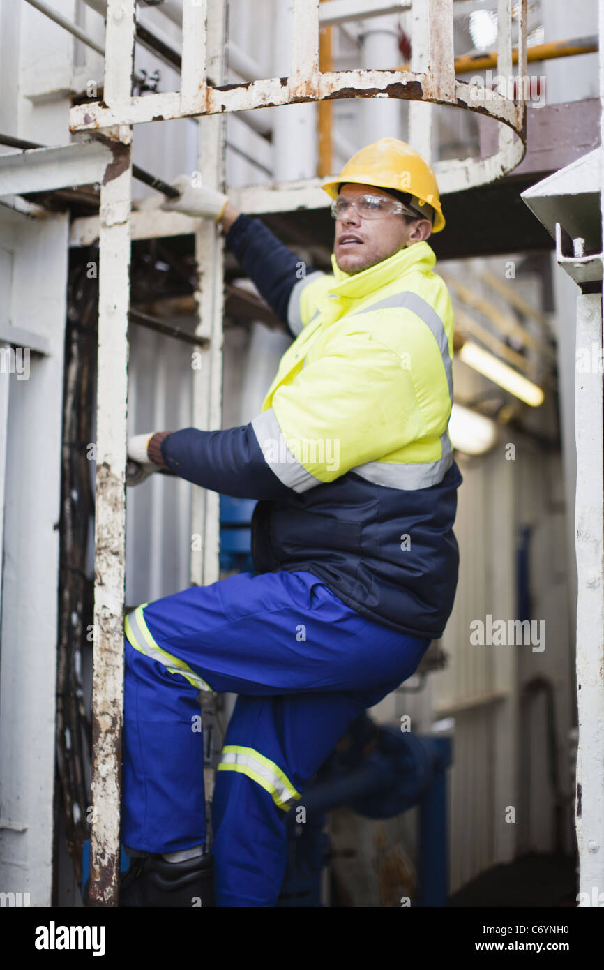 Worker climbing ladder on oil rig Stock Photo