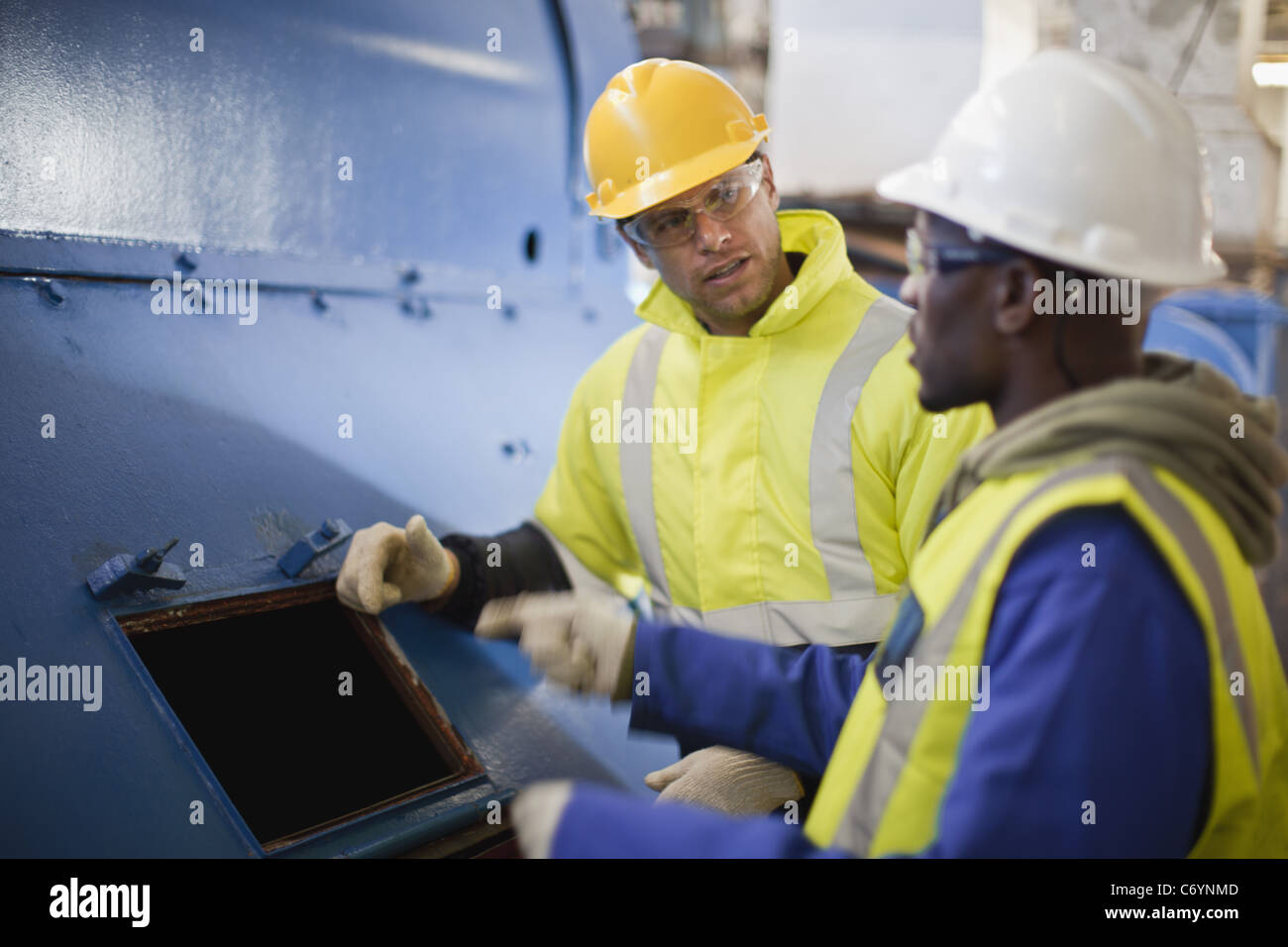 Workers examining machinery on oil rig Stock Photo