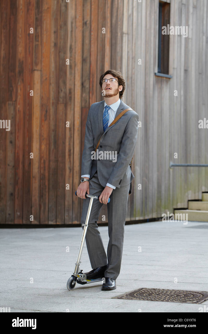 Businessman riding scooter in courtyard Stock Photo