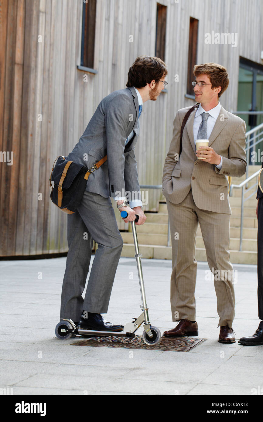 Businessman on scooter with colleague Stock Photo