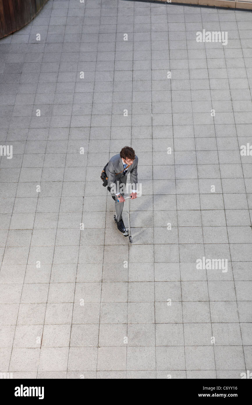 Businessman riding scooter in courtyard Stock Photo