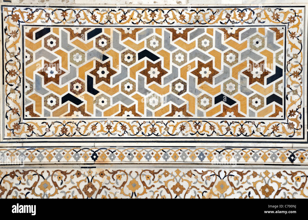A wall decorated with  a repeating pattern of regular shapes made from semi precious stones inlaid in white marble. Stock Photo