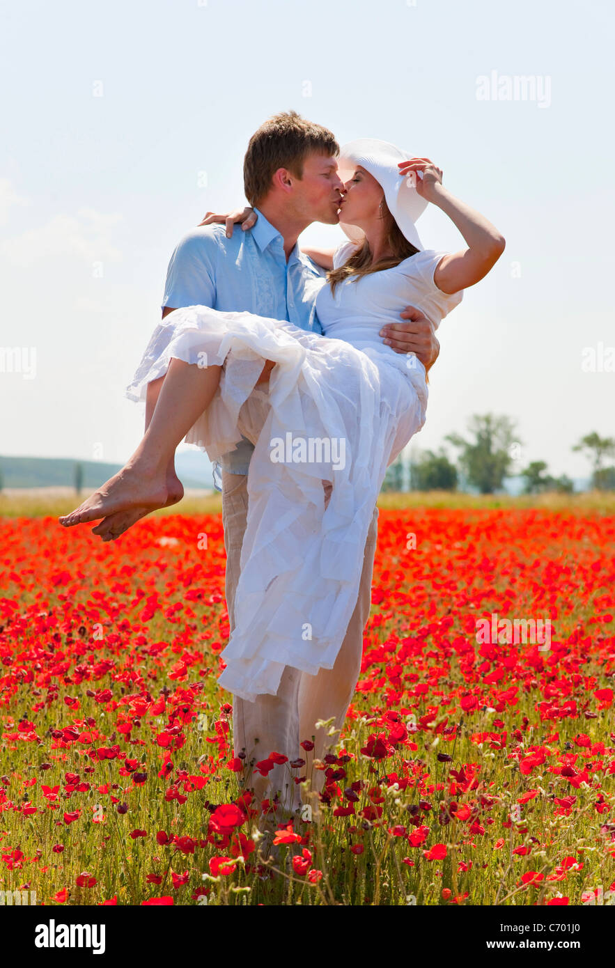 Couple kissing in field of poppies Stock Photo