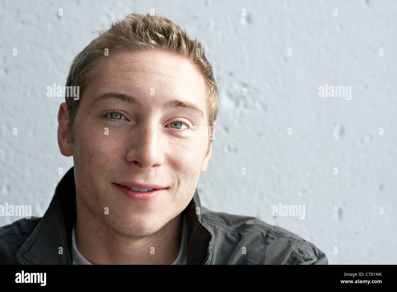 Close up portrait of a handsome smiling young man in his early twenties with dirty blonde hair. Stock Photo