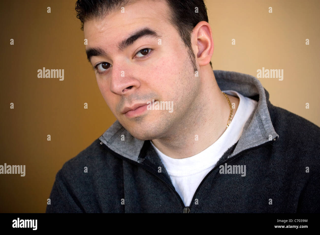 Portrait of a young man in his twenties over a golden background. Stock Photo