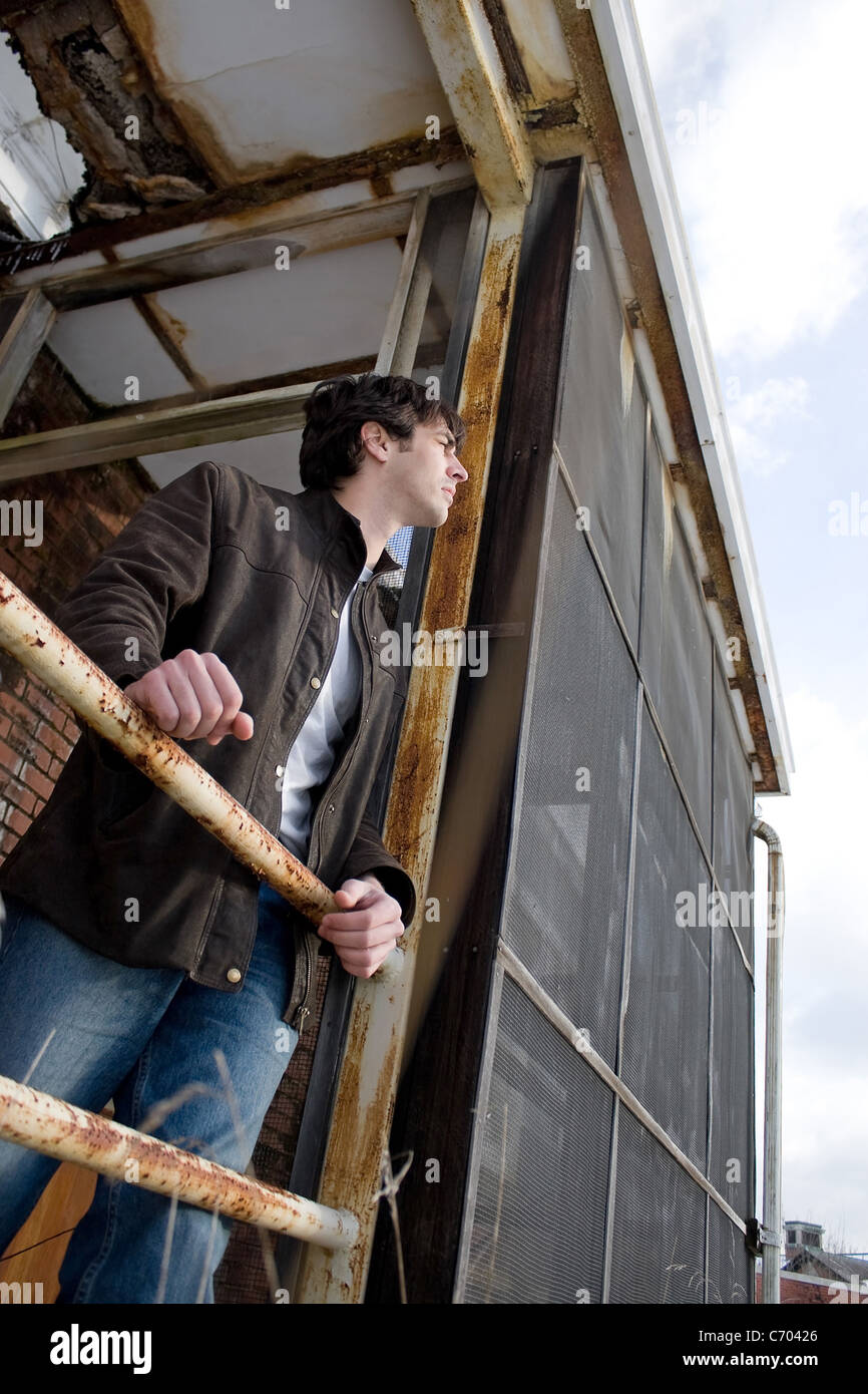 A young brunette man posing outside a worn and abandoned building. Stock Photo