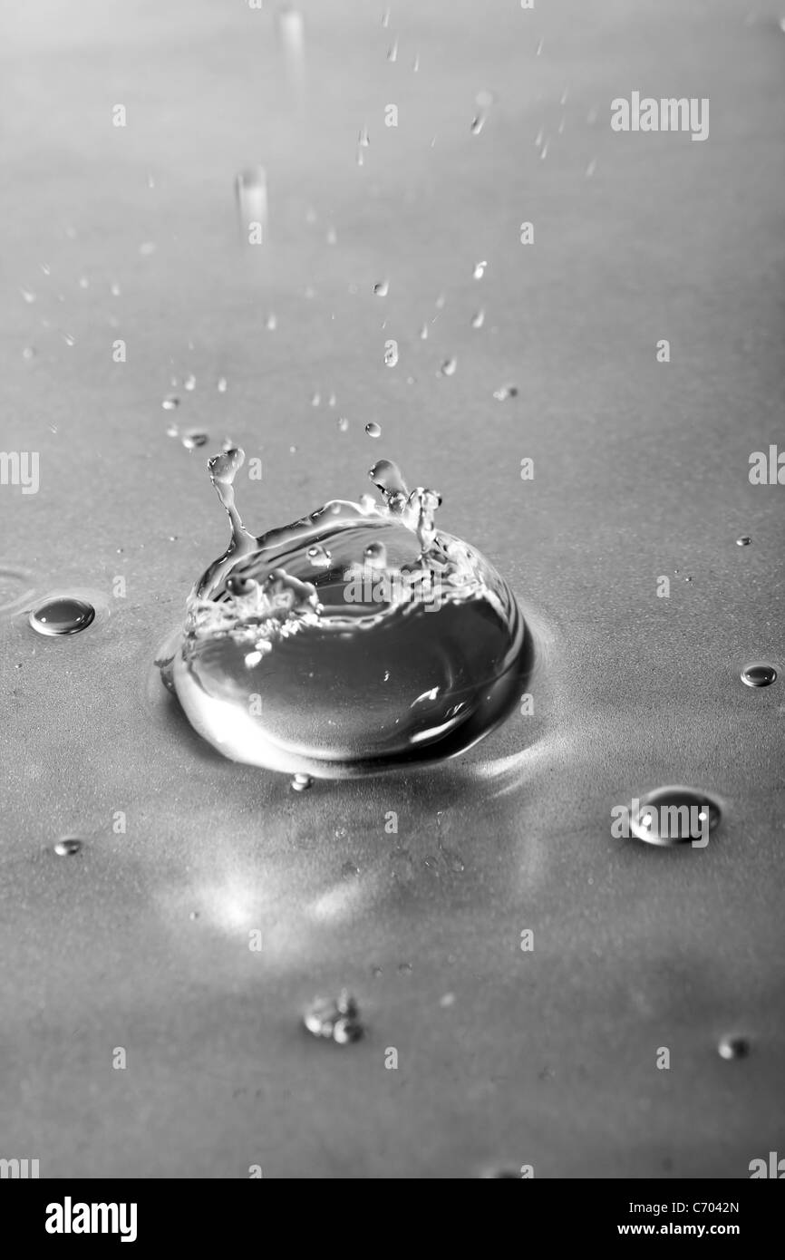 A clear water background texture and splash with droplets forming a crown shape. Shallow depth of field. Stock Photo